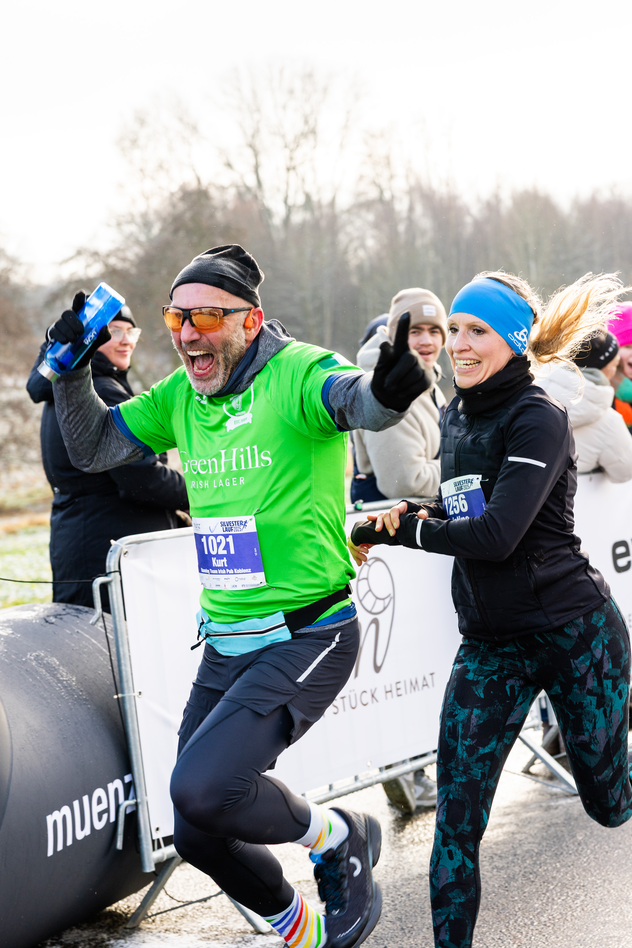Zwei fröhliche Läufer mit Daumen hoch beim Silvesterlauf